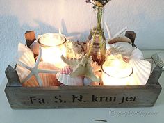 a wooden box filled with seashells and candles