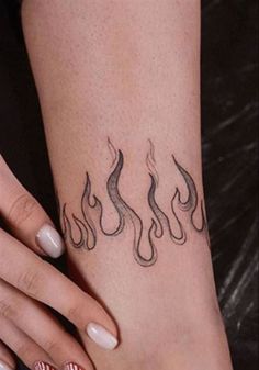 a woman's foot with a tattoo on it and flames coming out of the top