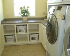 a washer and dryer in a small laundry room with white baskets on the floor