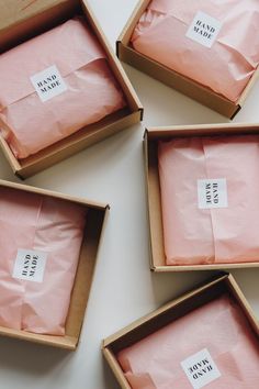 four boxes with pink tissue paper in them and one has a label on the top