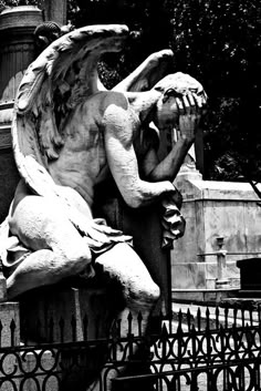 an angel statue sitting on top of a fence