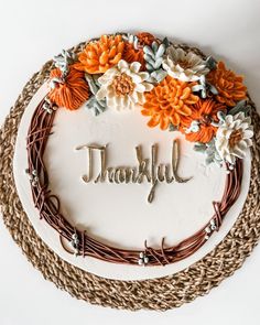 a cake with the word thank written on it and decorated with flowers, leaves and twigs