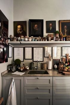 a kitchen with many pictures on the wall above the sink and below the countertop