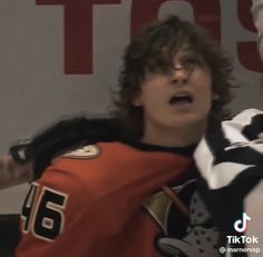 the young man is wearing an orange and black jersey while holding his arms out in front of him