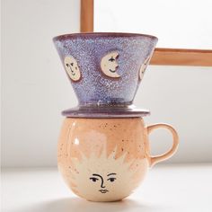 three ceramic cups with faces on them are stacked in the shape of a sun and moon