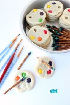 there are some cookies with paintbrushes in the bowl