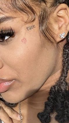 a close up of a person with tattoos on her face and hair in braids