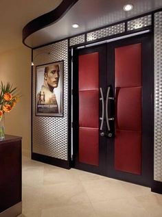 a red and black door in front of a brown wall with flowers on the floor