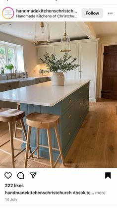 a kitchen with two stools and an island in the middle of it, surrounded by wood flooring