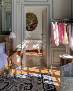 an open door leading into a bedroom with clothes hanging on the wall and a tub in the corner