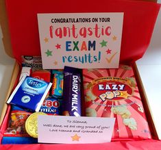 an open red box filled with candy and other items next to a sign that says congratulations on your fantastic exam results