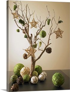 a tree with ornaments in it sitting on a table next to some balls and branches