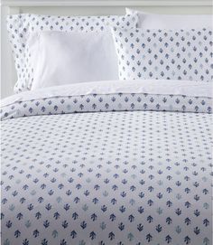 a bed with blue and white bedspread, pillows and pillow cases on it