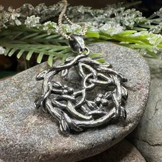 a silver pendant sitting on top of a rock