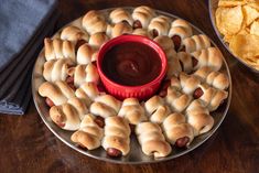 a plate with pigs in a blanket on it next to a bowl of dipping sauce