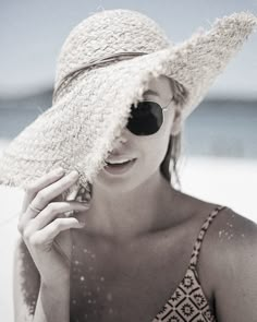 a woman wearing a hat and sunglasses on the beach