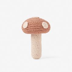 a crocheted mushroom is shown on a white background, with two small buttons at the top