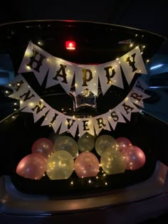 a happy winter's day sign is lit up with balloons and streamers in the dark