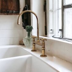 a bathroom sink with two faucets and a vase on the counter next to it