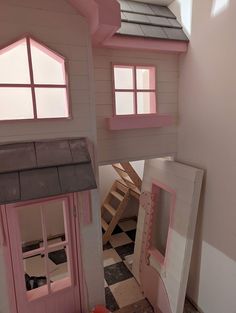 there is a doll house made out of wood and pink paint on the inside of it