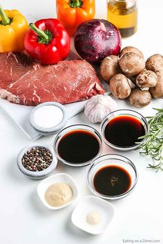 raw meat, vegetables and sauces on a white surface