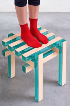 a person wearing red socks standing on top of a small stool with legs that are bent down