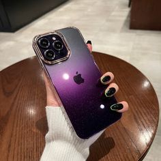 a woman is holding up her phone case with purple and black ombretta on it