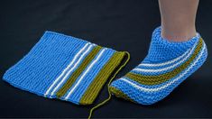 a knitted blue and green sock with white stripes next to a pair of feet