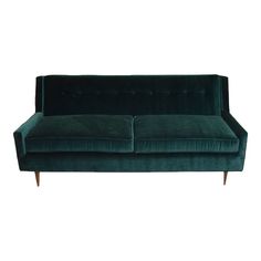 a green velvet couch with wooden legs