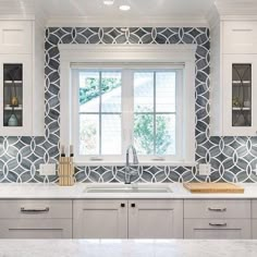 a kitchen with marble counter tops and white cupboards next to a window in the wall