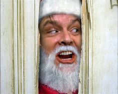 an old man wearing a santa claus hat looking through a door with his mouth wide open