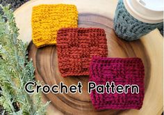 three crocheted dishcloths sitting on top of a wooden plate next to a plant