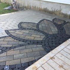 an outdoor patio with cobblestone pavers and brick edging in the shape of a flower