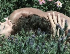 a man is laying in the bushes with his head on his chest and eyes closed