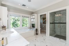 a large white bathroom with a walk in shower next to a bathtub and sink