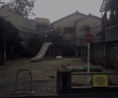 an empty yard with a slide in the middle and no children allowed sign next to it