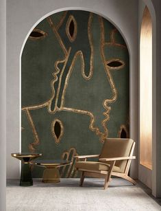 a chair and table in front of a wall with an abstract painting on the wall