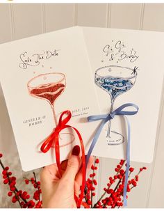 two handmade cards with wine glasses on them, tied to red berries and blue ribbon