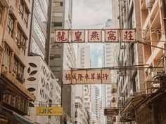 a city street with lots of tall buildings and chinese writing on the signs above it