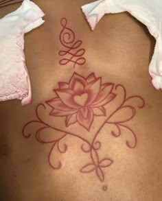 a woman's back with a flower tattoo on her lower back and the word love written in red ink