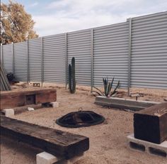 a wooden bench sitting in the middle of a dirt field next to a metal fence