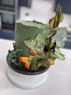 a green hat with fish and plants on it sitting on a white table in a kitchen