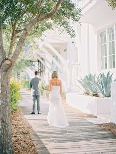 the bride and groom are walking down the sidewalk