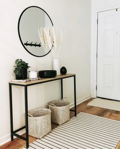 a table with two baskets and a mirror on the wall above it in a white room