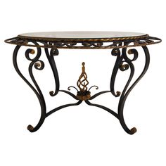 a table that has a glass top and metal legs on it with an ornate design