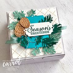 a box with some cookies in it on top of a white table and the words season's greetings