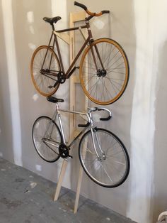 two bikes are mounted to the wall with wooden pegs