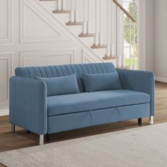 a blue couch sitting on top of a wooden floor next to a stair case in a living room