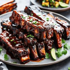 barbecued ribs with sauce and garnish on a plate next to lime wedges