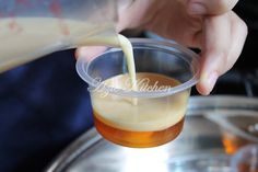 a person pouring liquid into a cup on top of a metal tray with food in it